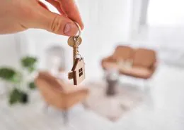 Comment déléguer la gestion locative en toute sérénité ? 1 homme tenant une clé et un porte clé de maison dans sa nouvelle propriété